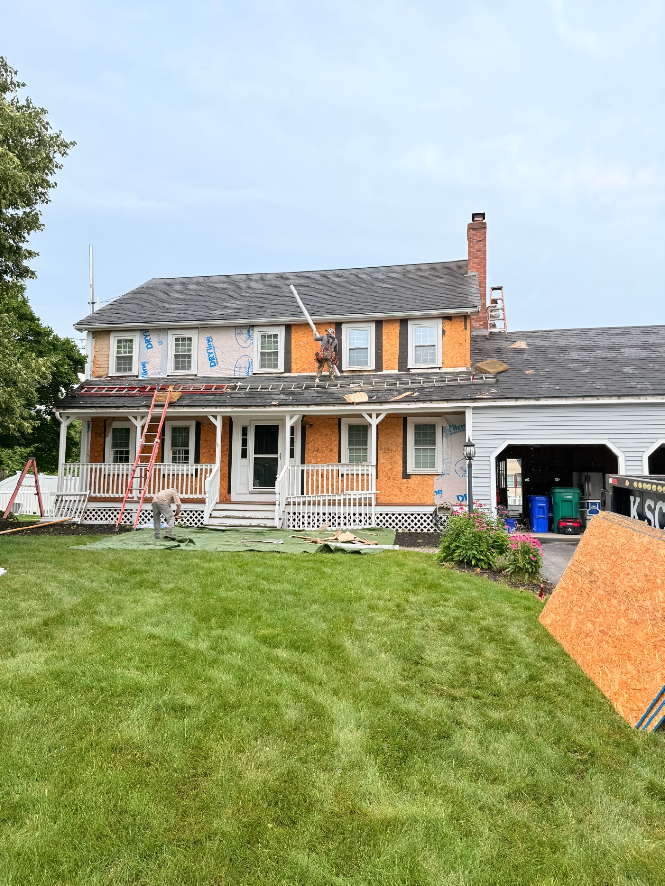 Front view during tear-off showing exposed sheathing and crew working